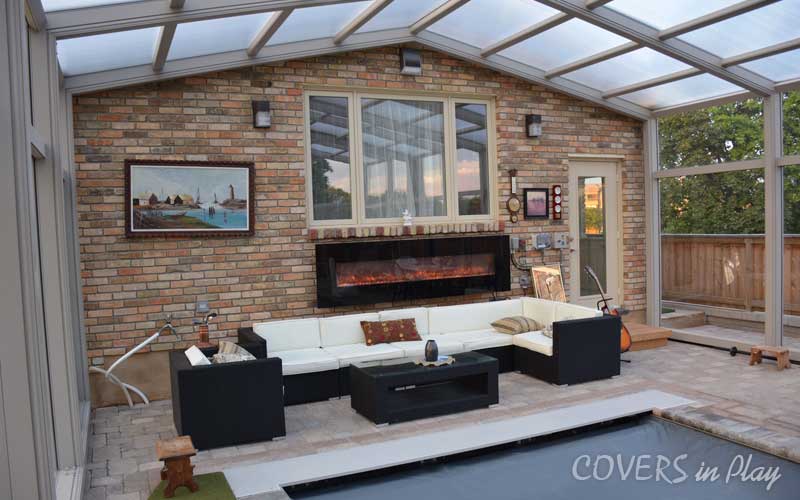 Inside close-up view of a closed pool enclosure with fireplace and couches in Burlington